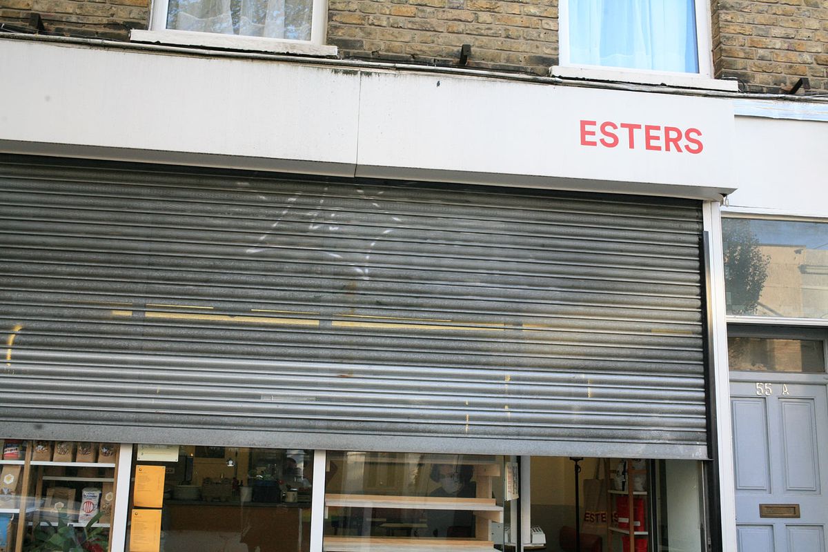 The frontage of Stoke Newington Cafe Esters, with a grey shutter rolled down halfway