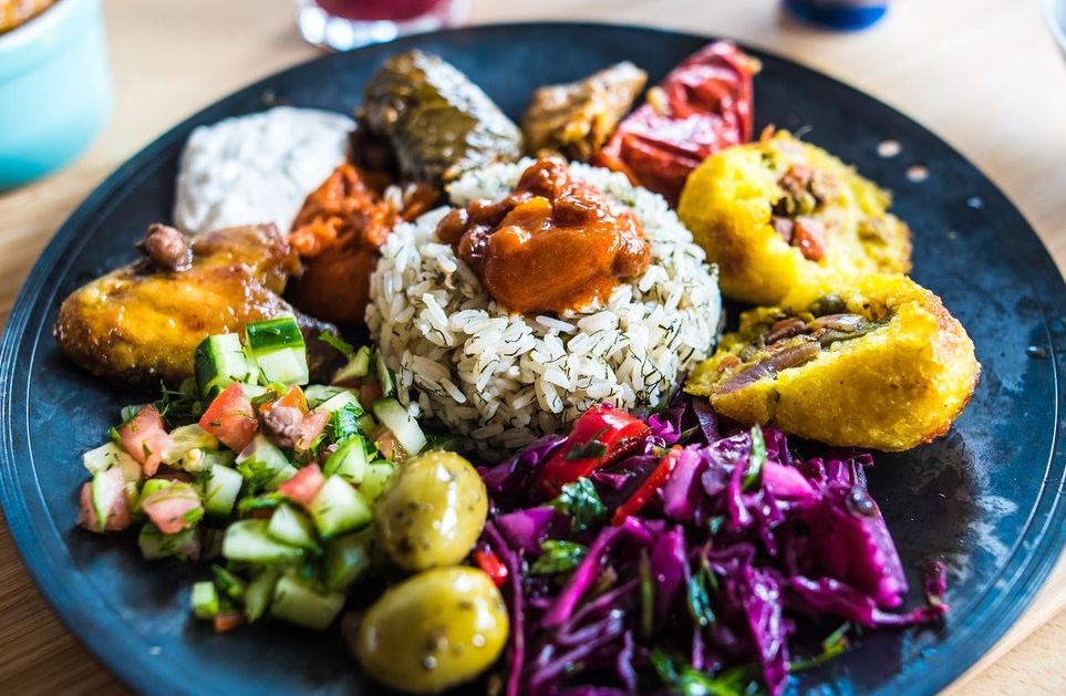 A mezze platter with various dishes surrounding a mound of rice. 