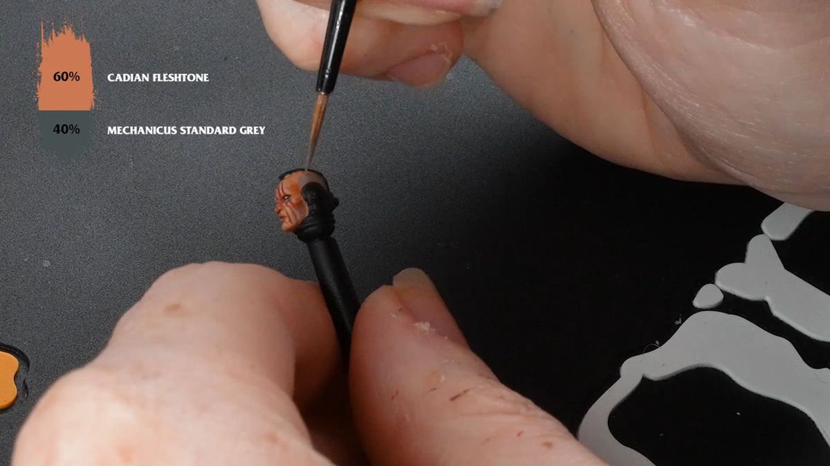 A pair of hands painting the stubble on the head of a Space Marine