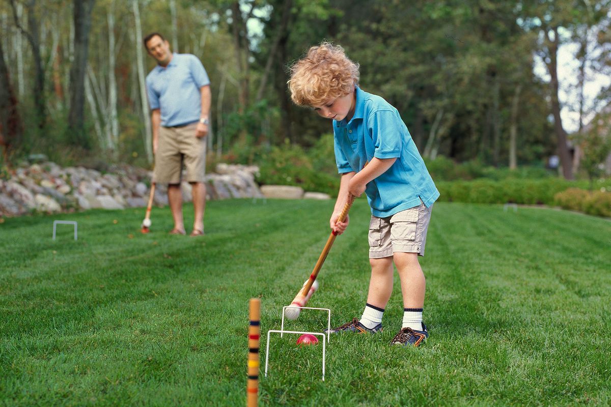 Family playing croquet in backyard
