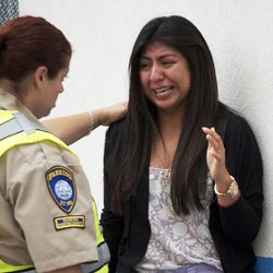 Priscilla Morales cries as she is consoled by a parking enforcement officer Friday June 7, 2013 in Santa Monica, Calif.  Morales was in the library at Santa Monica College, where a gunman who allegedly killed at least six people with an assault-style rifle was shot to death in a gunfight with police. 