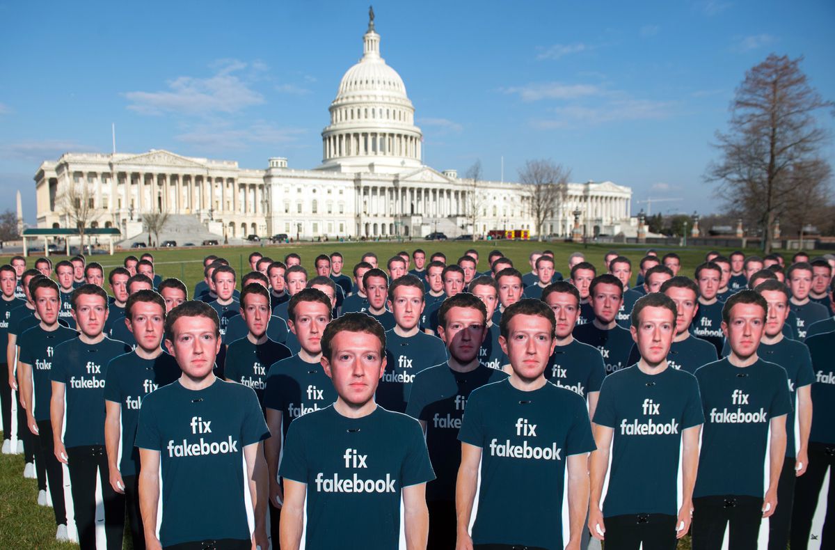 A crowd of identical cardboard cutouts of Mark Zuckerberg wearing a “fix Facebook” T-shirt on the lawn of the Capitol building.
