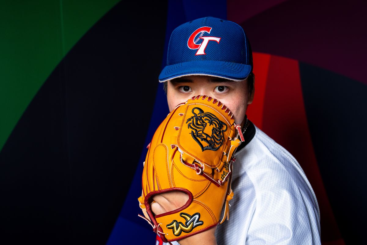 Kai-Wei Teng holding a glove over his face and posing for a photo during WBC media day