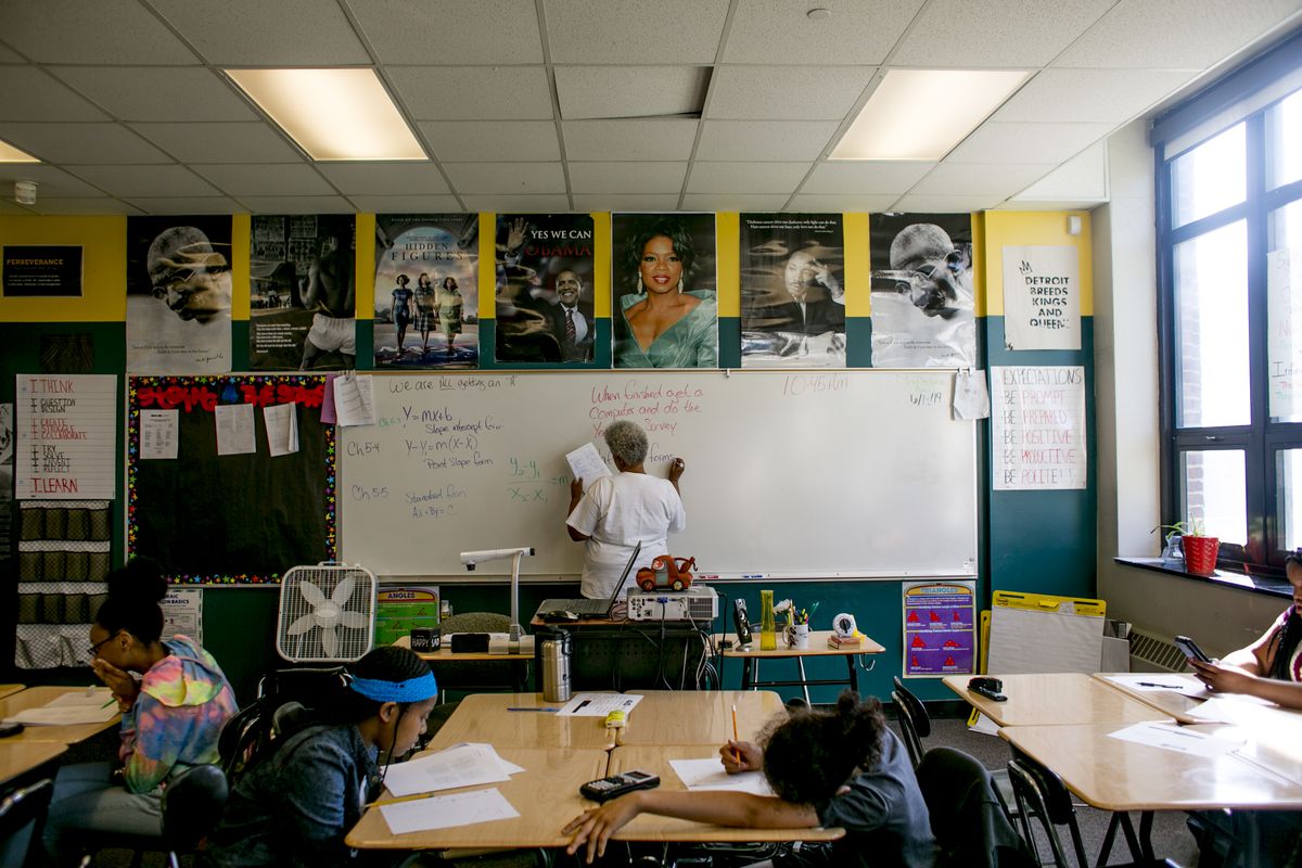 As students work at their desks, a teacher writes on a board in a math class at Southeastern High School in Detroit, MI. Photo by Anthony Lanzilote/Chalkbeat; Taken June, 2019