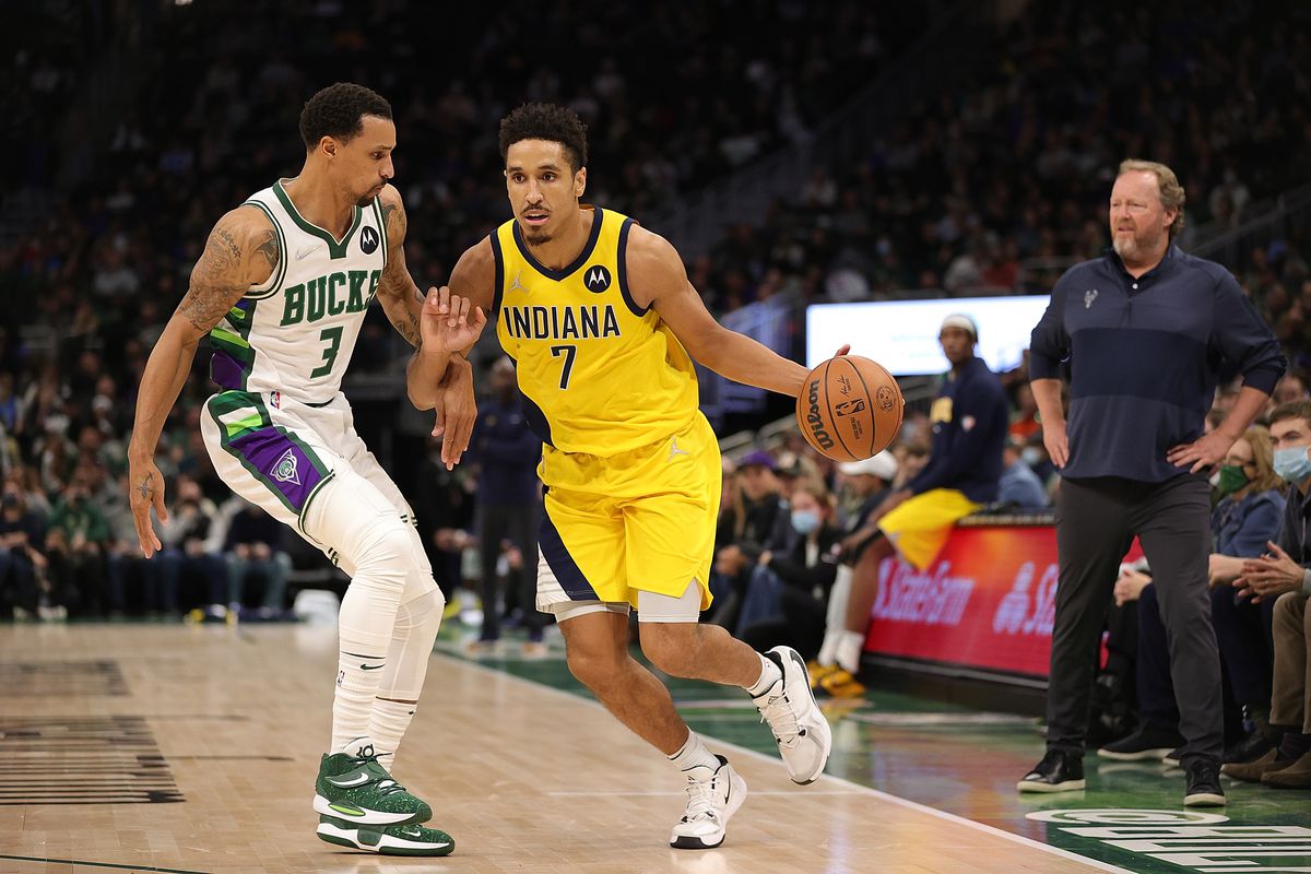 Malcolm Brogdon #7 of the Indiana Pacers drives around George Hill #3 of the Milwaukee Bucks during a game at Fiserv Forum on December 15, 2021 in Milwaukee, Wisconsin.