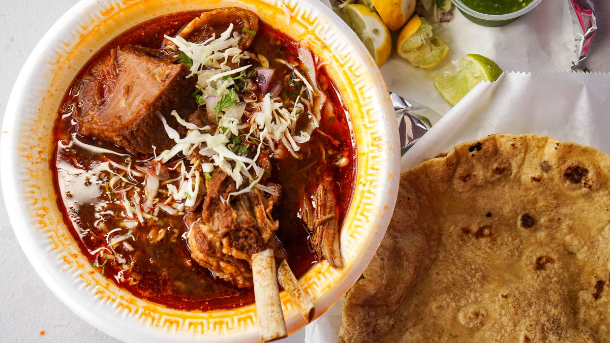 Red-tinted roast goat with a side of fresh tortillas.