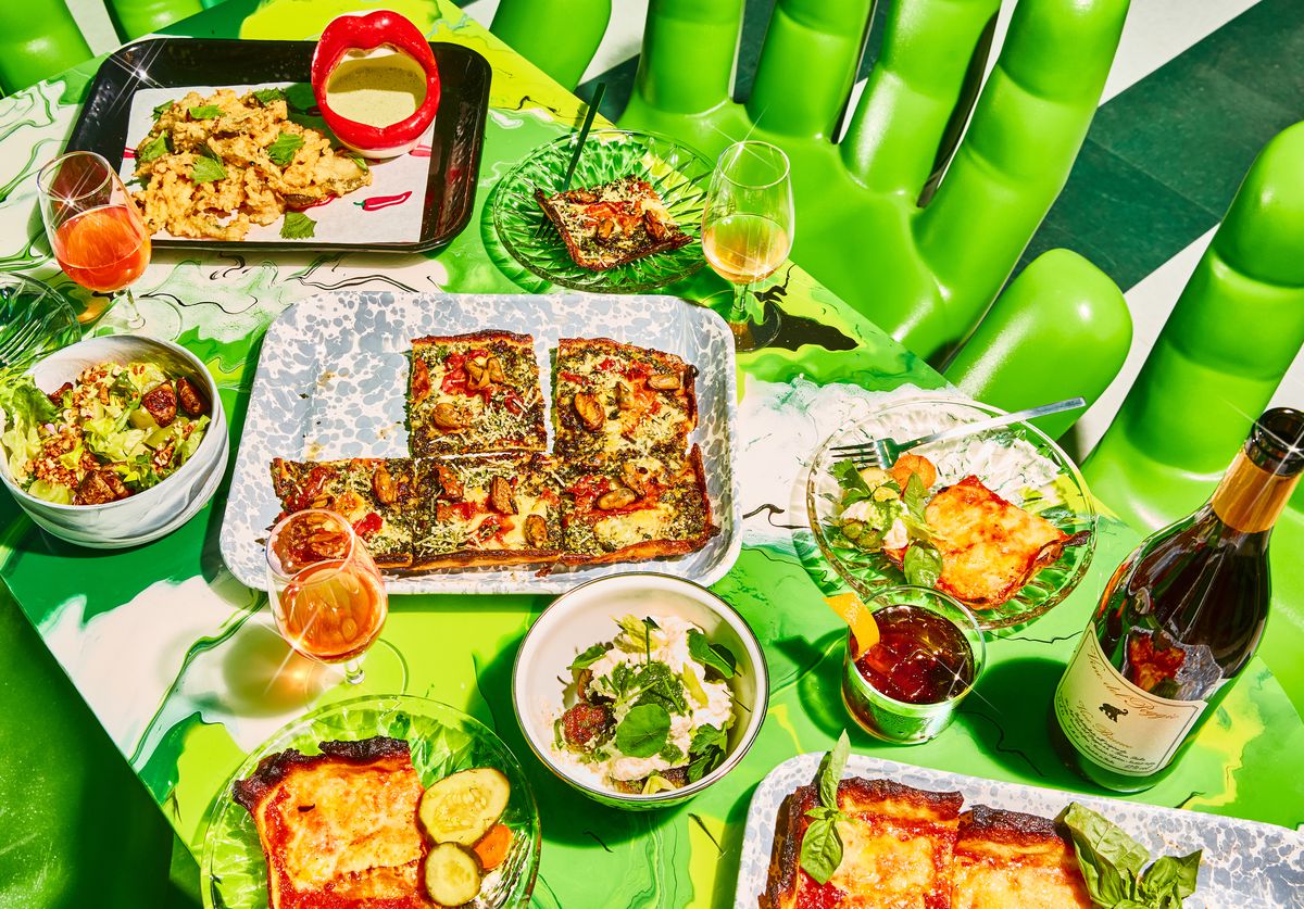 A lime green table laid out with pizzas and other food.