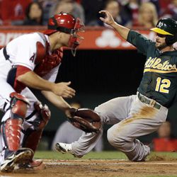 Oakland Athletics' Andy Parrino, right, scores past Los Angeles Angels catcher Chris Iannetta on a single by Jed Lowrie during the third inning of a baseball game in Anaheim, Calif., Thursday, April 11, 2013. 