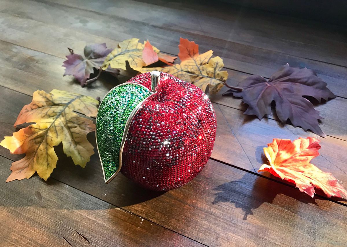 A red crystal bag from Judith Leiber, arranged near some leaves