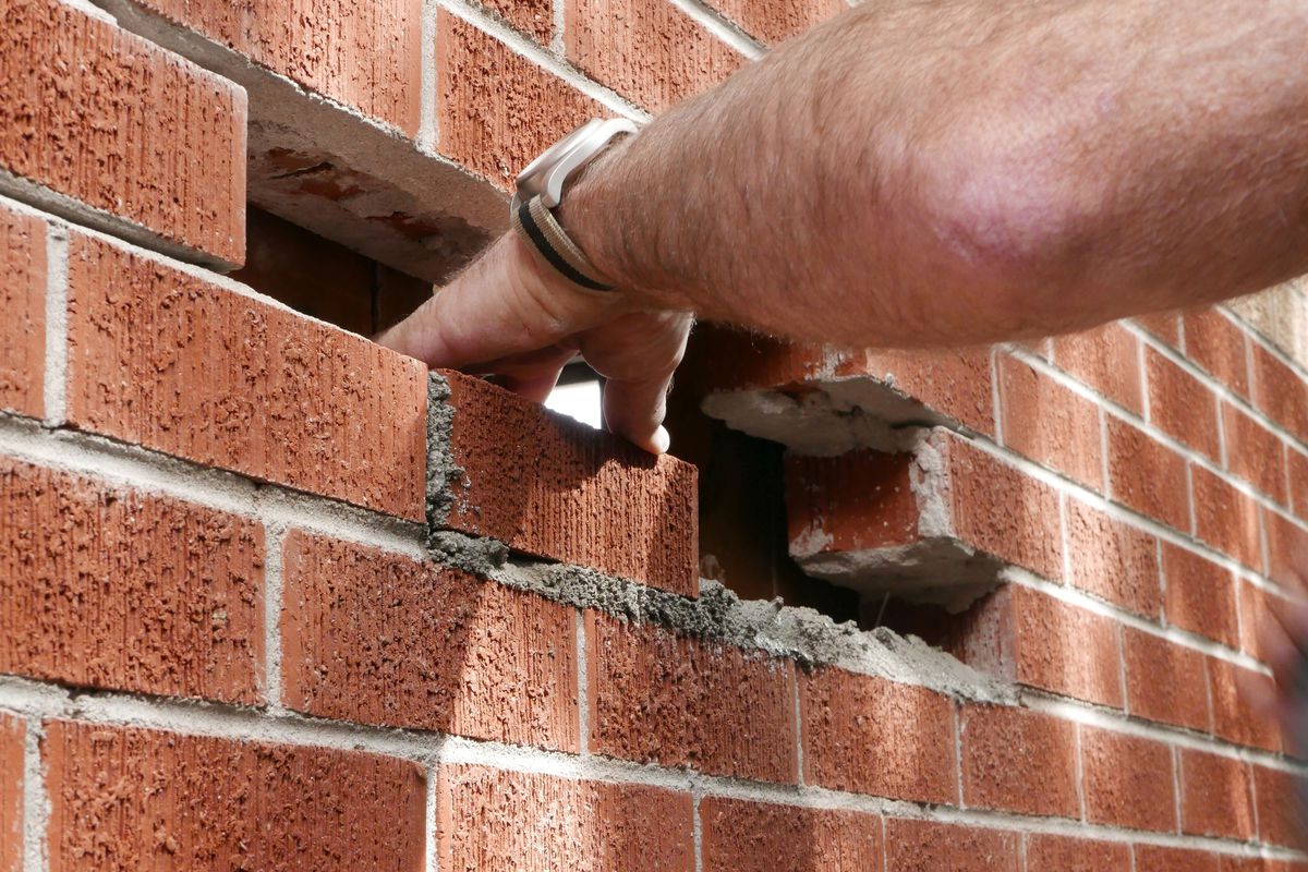 A mason repairing a hole in a brick wall.