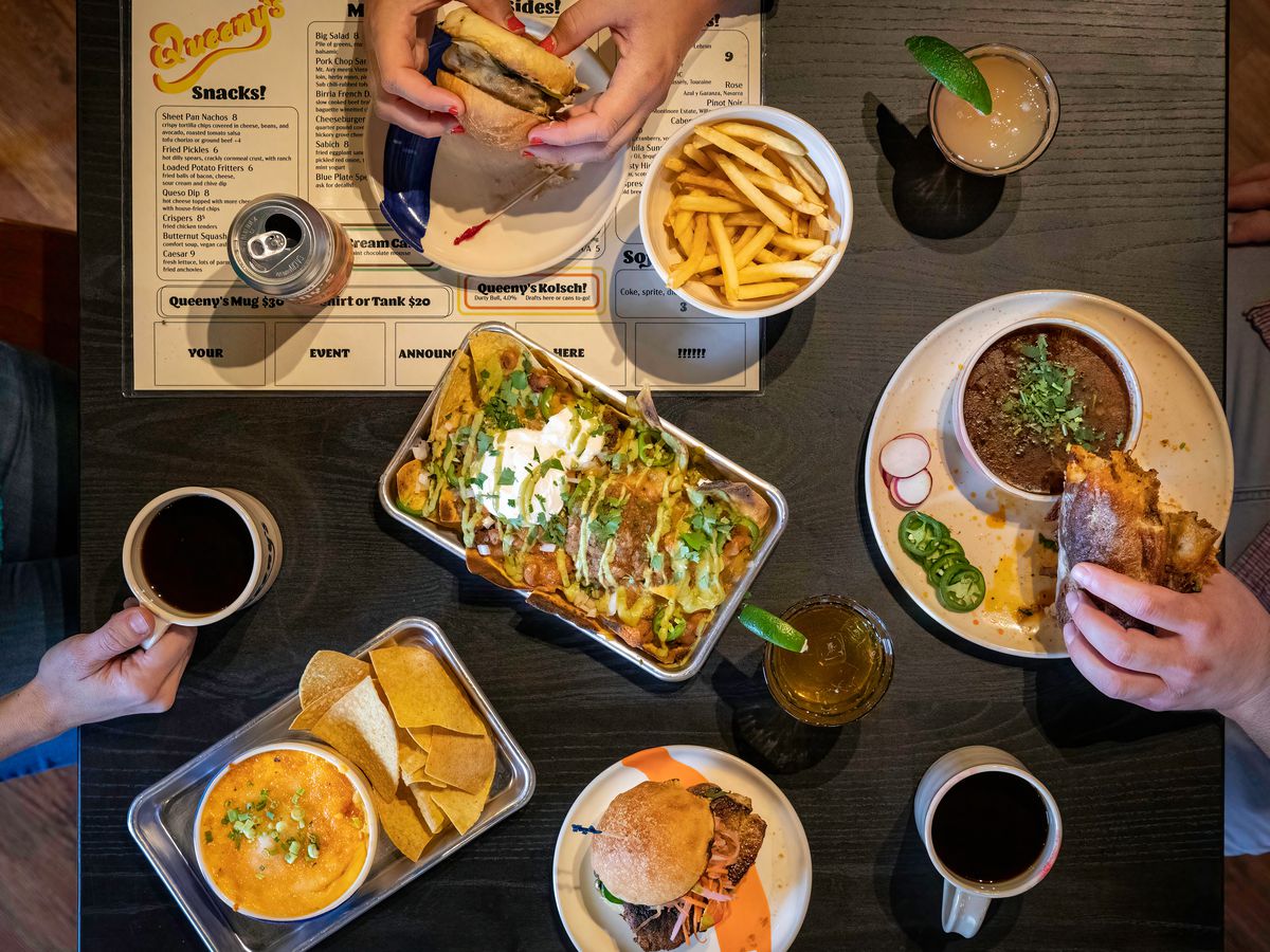 Food on a table with hands holding coffee mugs.