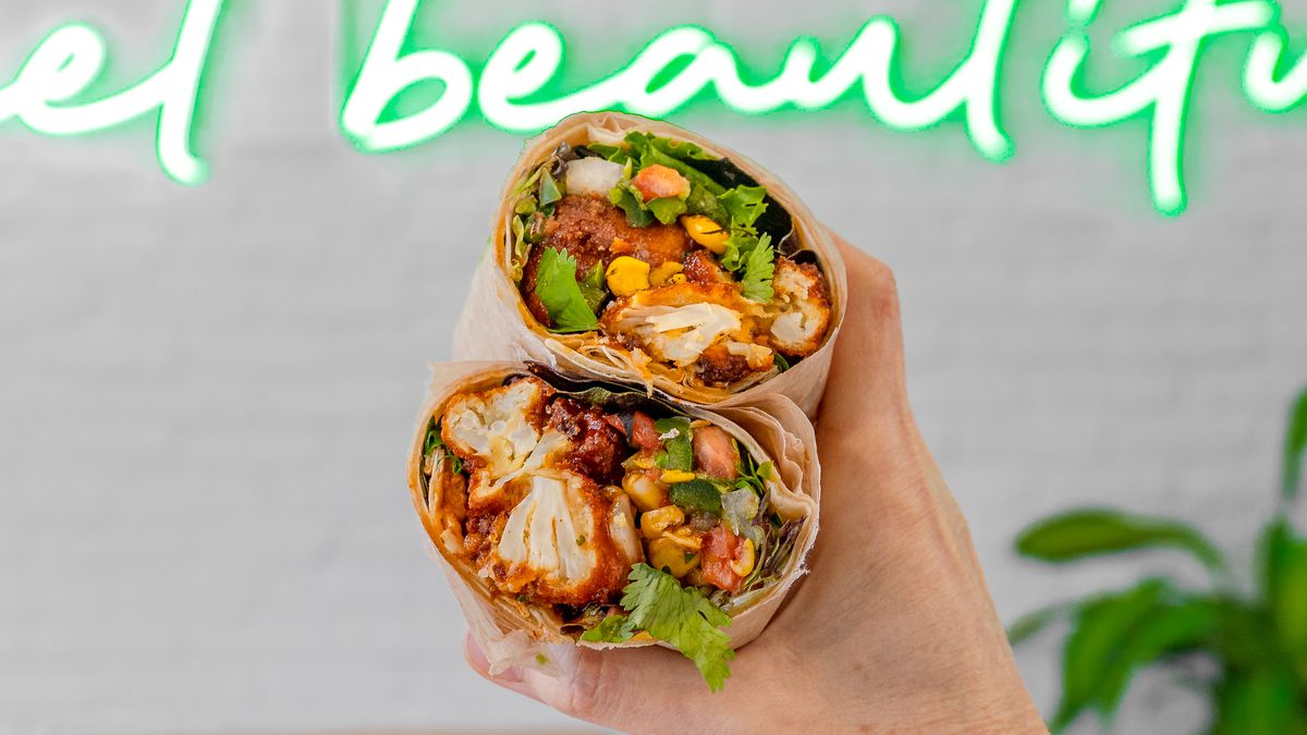 A hand holds up a vegetarian burrito.