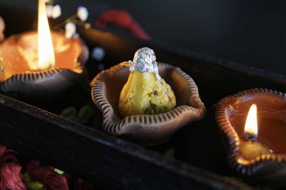 Three Diwali diyas with an offering.