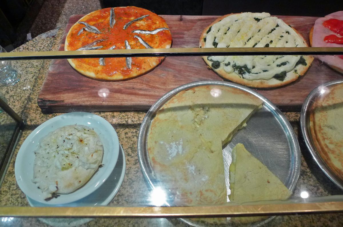 A glass case with five or so pies on display.