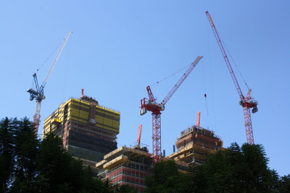 The tops of three under-construction towers and a trio of cranes.
