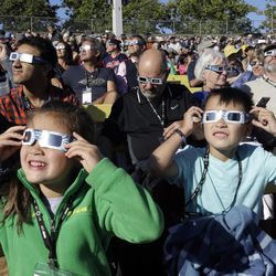 A crowd wears protective glasses as they watch the beginning of the solar eclipse from Salem, Oregon., Monday, Aug. 21, 2017.