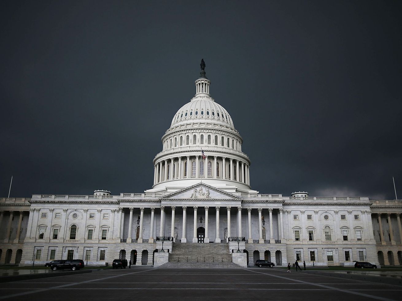 The US Capitol building with dark clouds behind it.