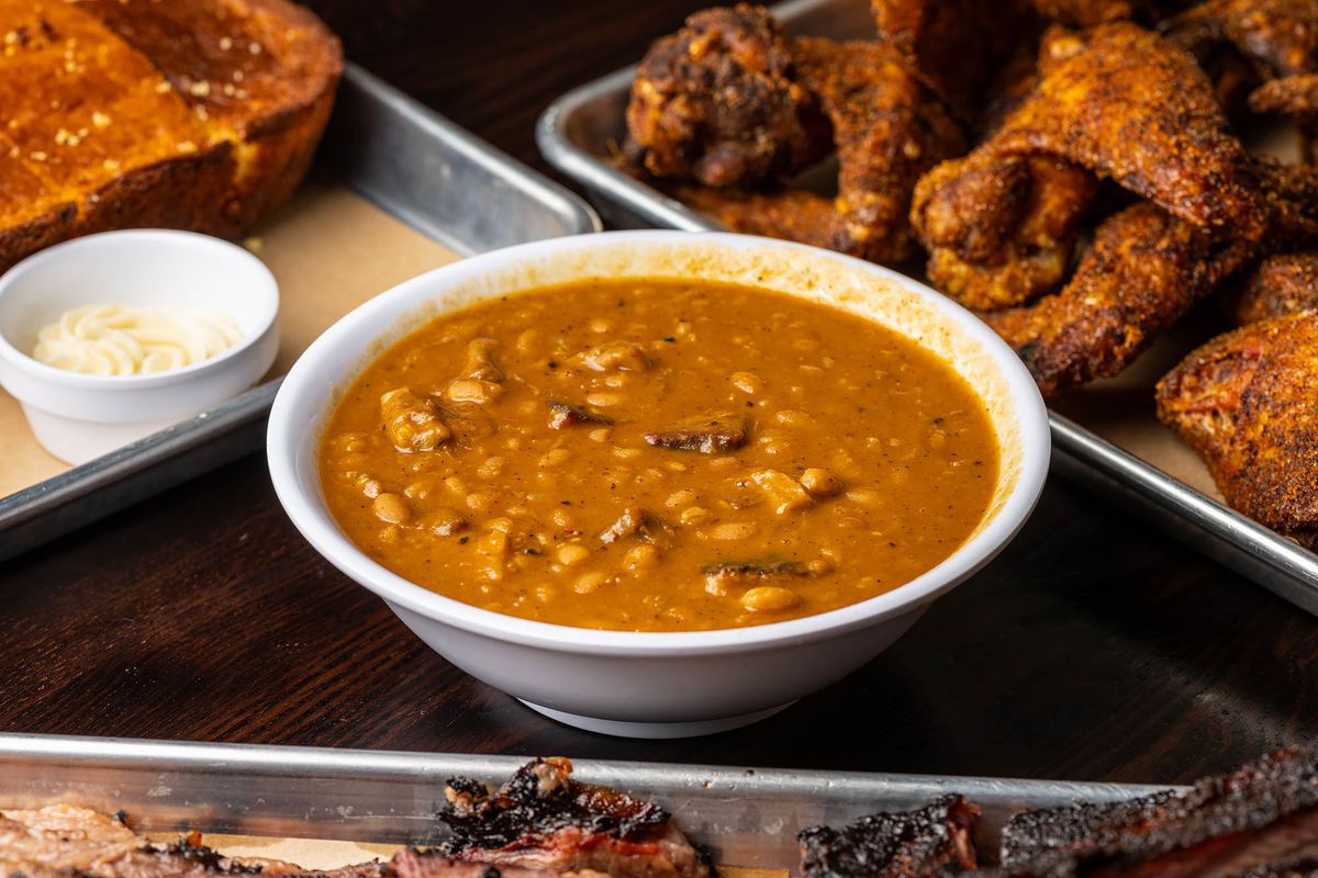 A bowl of baked beans sits between barbecue at Bludso’s BBQ in Santa Monica.