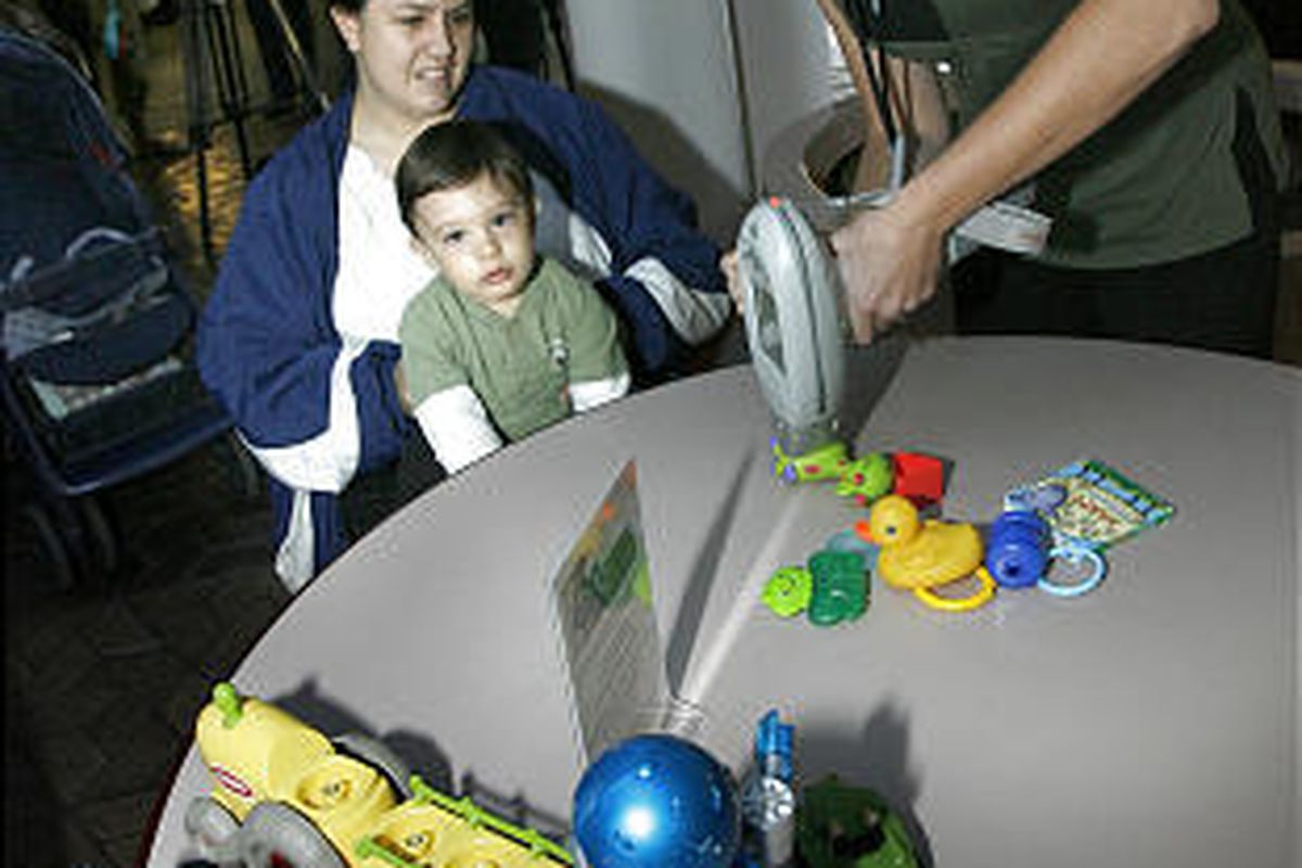 Angela Petersen and her son, Justin, watch as Vanessa McMillan of the Salt Lake County Health Department checks Justin's toys for lead. The metal can be especially harmful to young children.