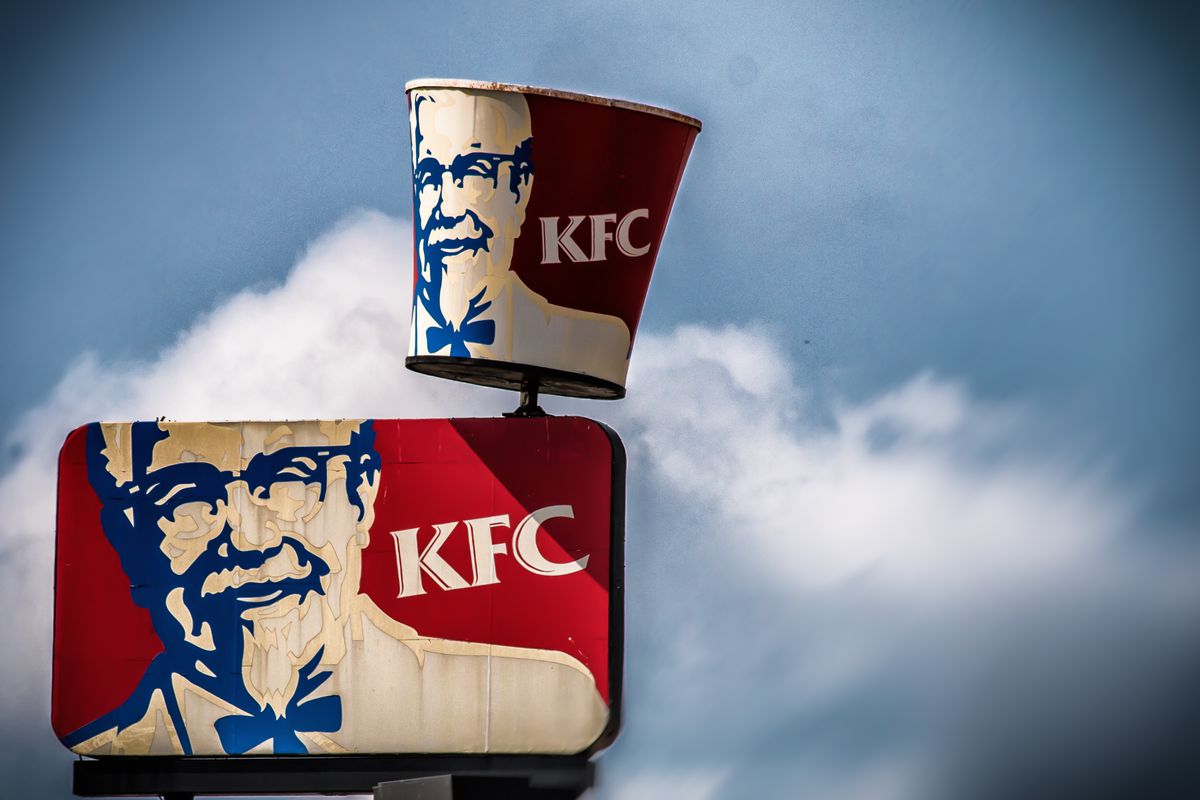 A sign for KFC against a clouded sky