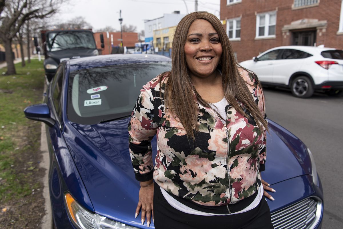 Felicia Brown an Uber, Lyft and Instacart driver, stands next to her vehicle.