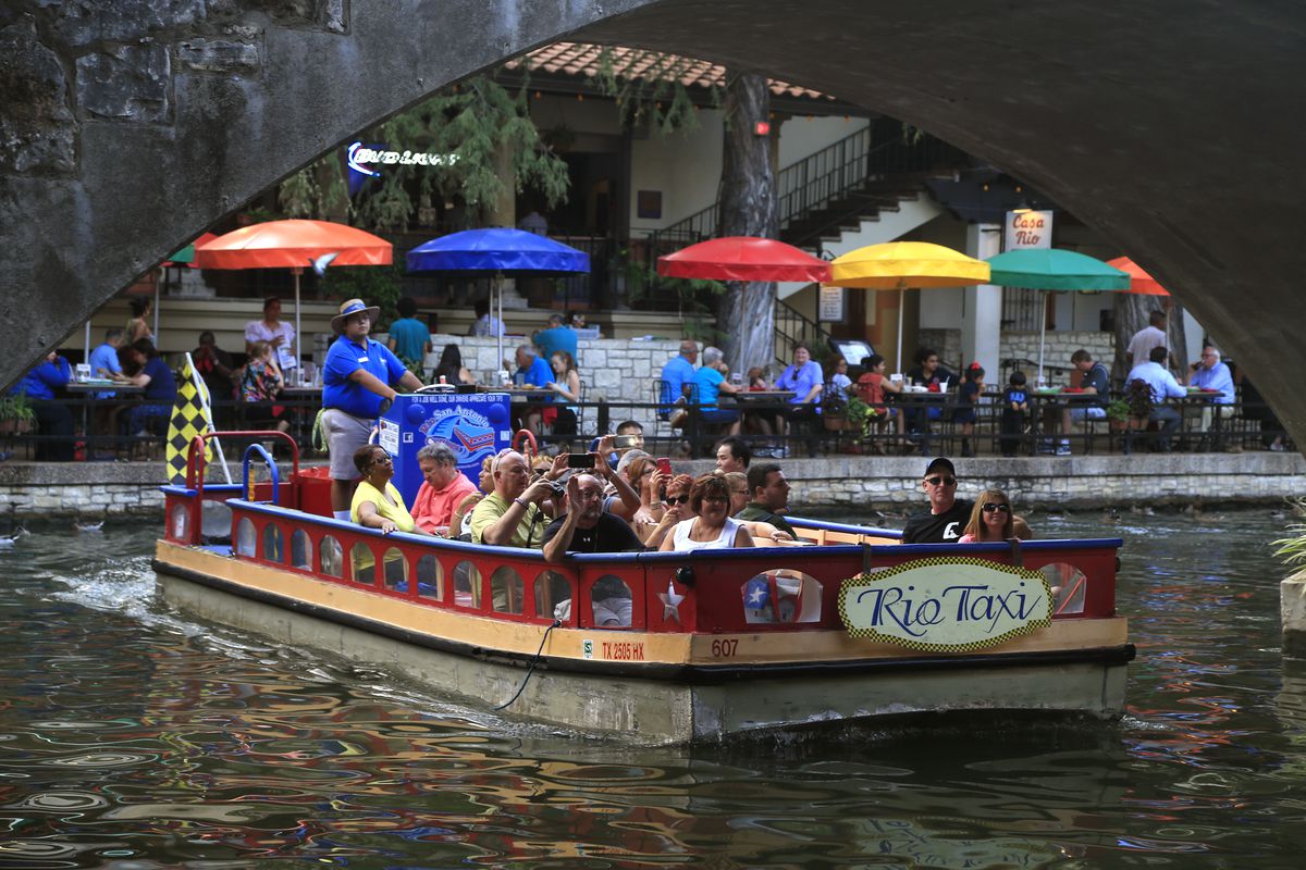 SAN ANTONIO, TX., SEPTEMBER 15, 2014: One of the Rio Taxi boats floats past the colorful umbrellas a