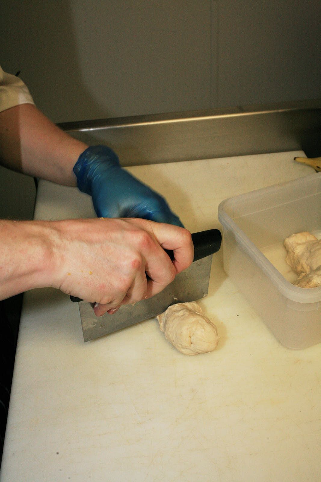 A cook portions dough with a benchscraper.