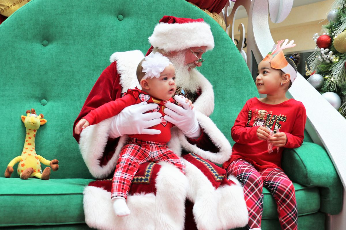 A mall Santa hangs out with two young children.