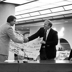 Sam Battistone, left, accepts an $8 million check from Larry H. Miller as Miller buys Battistone's half of the team.