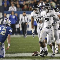 Utah State Aggies safety Jontrell Rocquemore (3) is mobbed by his teammates after stripping Brigham Young Cougars quarterback Tanner Mangum (12) of the ball and re3covering the fumble for a turnover during the Utah State versus BYU football game at LaVell Edwards Stadium in Provo on Friday, Oct. 5, 2018.