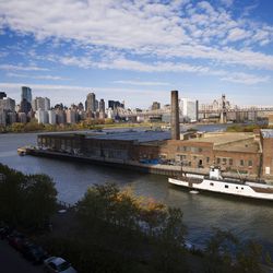 In this Wednesday, Nov. 7, 2018, photo, a rusting ferryboat is docked next to an aging industrial warehouse on Long Island City's Anable Basin in the Queens borough of New York. Across the East River is midtown Manhattan, top left. Long Island City is a longtime industrial and transportation hub that has become a fast-growing neighborhood of riverfront high-rises and redeveloped warehouses, with an enduring industrial foothold and burgeoning arts and tech scenes. (AP Photo/Mark Lennihan)