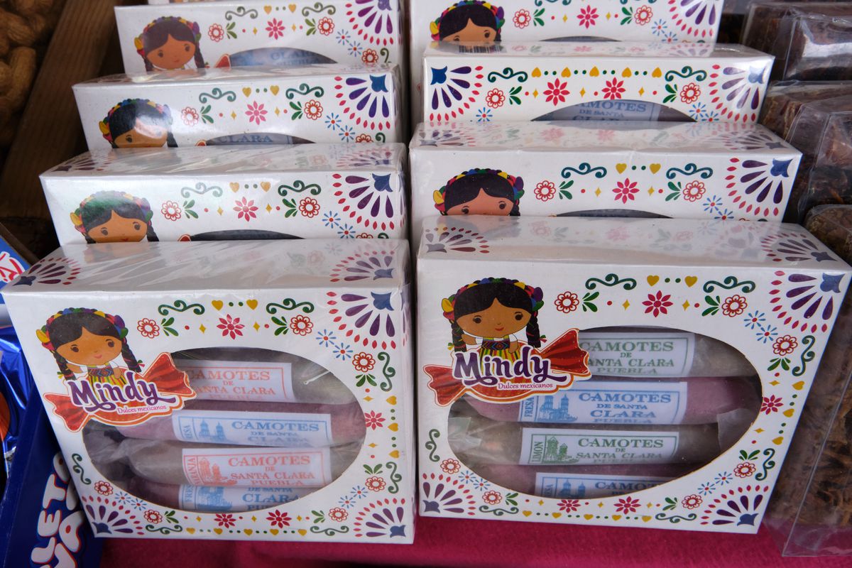 Six boxes of camotes, packaged in cardboard boxes covered with illustrated flowers, in a display.