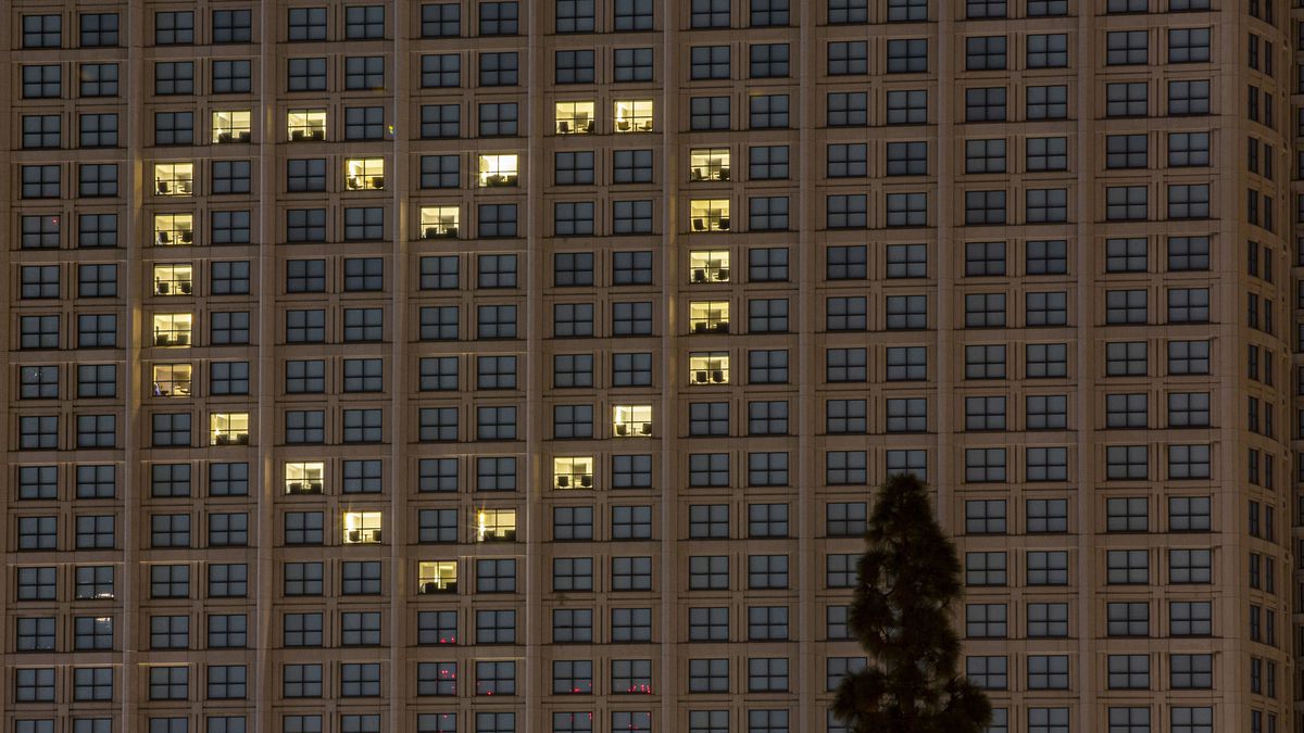 Lights in empty hotel rooms are turned on to create a heart in a large stucco building.