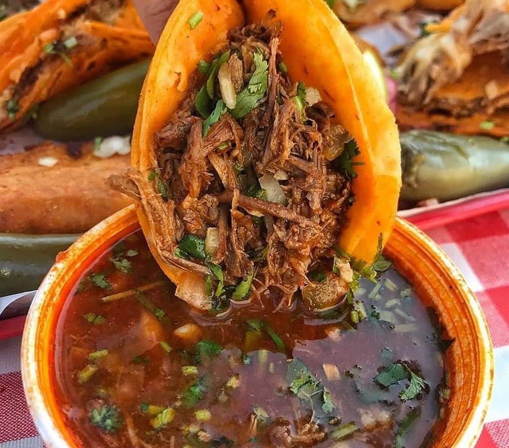 A taco being dipped in consomme