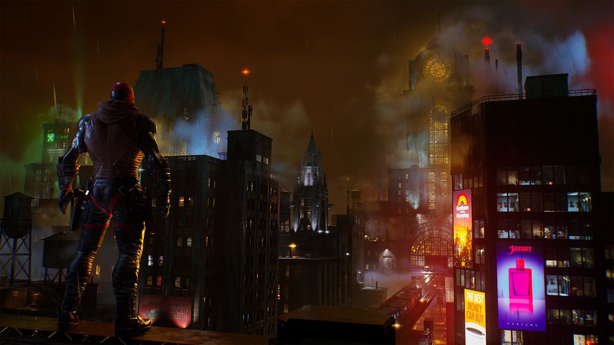 Red Hood, with his back to the camera, surveys Gotham City in Gotham Knights