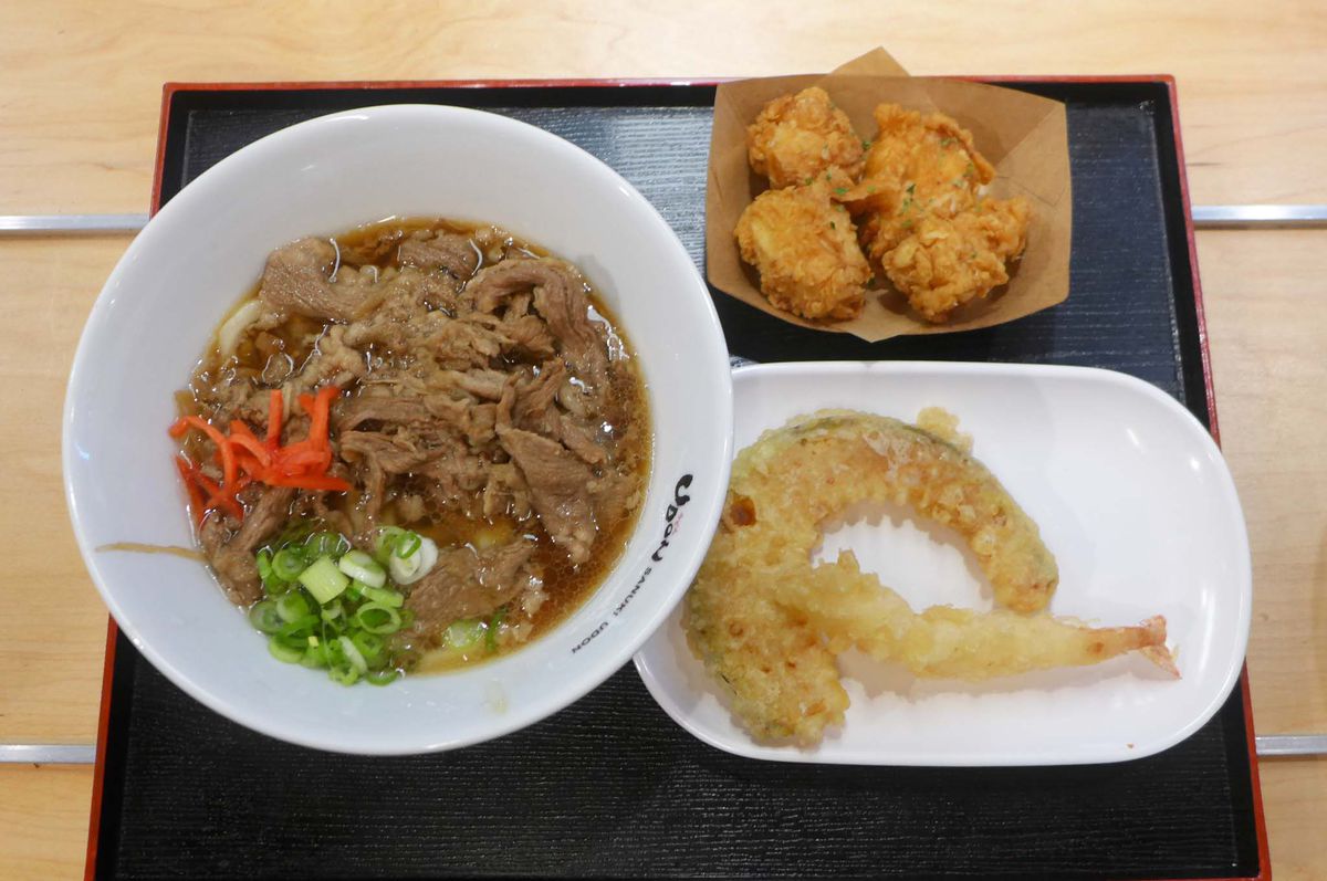 A bowl with beef wadded in it and a side plate with tempura.