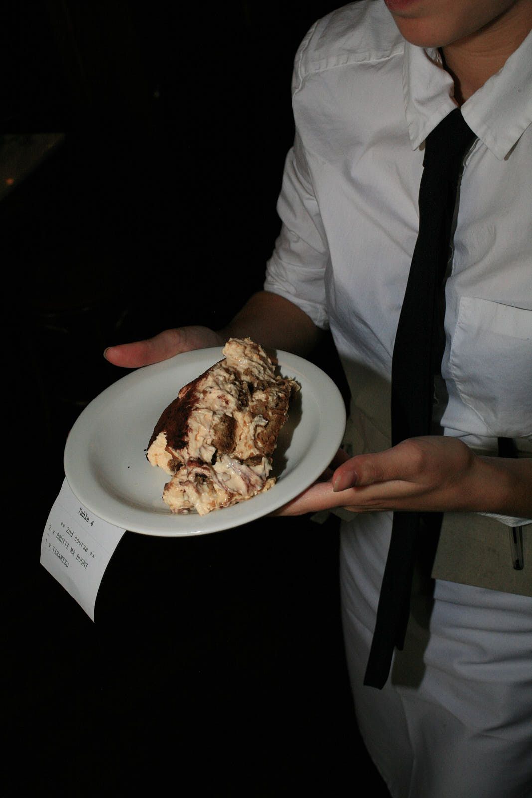 A plate of tiramisù is ferried to a table.