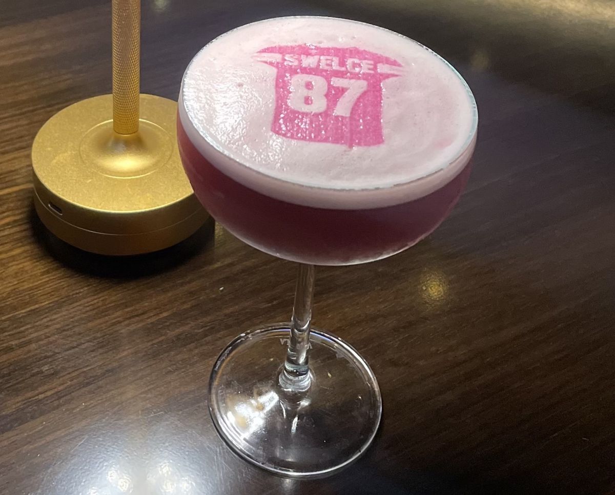 A pink cocktail with an image on a jersey laid into a foam topping. 