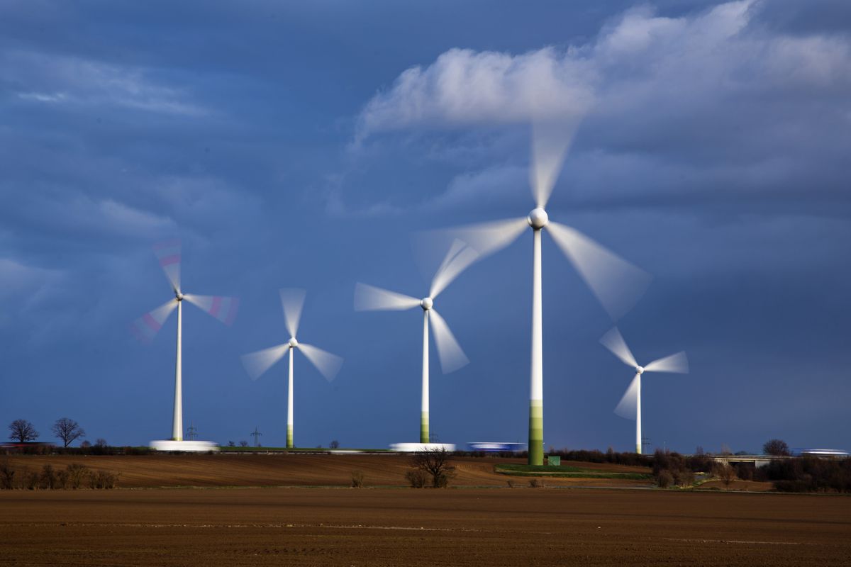Turning wind turbines of an onshore wind farm standing on a field on March 15, close to Stoessen, Germany. Renewable energy sources like wind power are fed into the power grid.