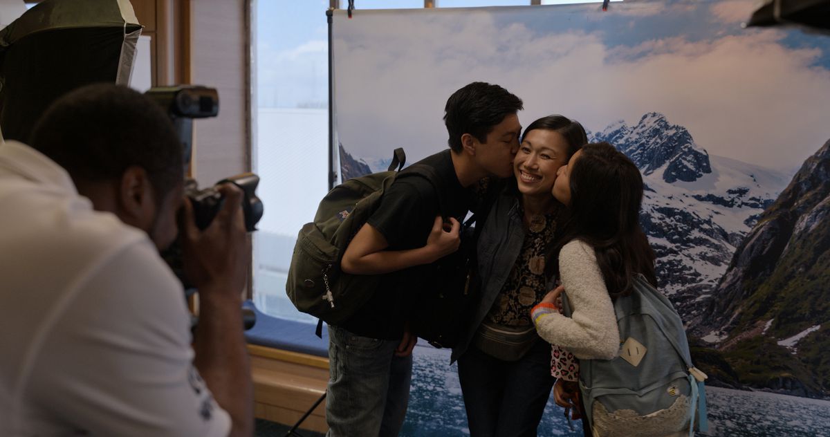 two kids kiss their mother’s cheeks as a cameraman takes the photo in Little America