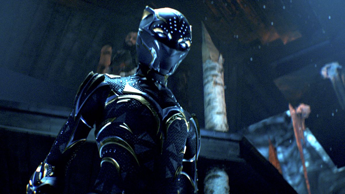 Shuri in her gold-streaked Black Panther suit, standing in a dark throne room, in Black Panther: Wakanda Forever