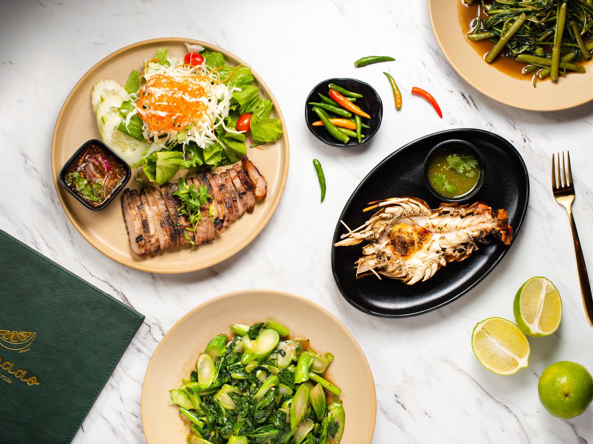 An array of Thai dishes over a marble tabletop.