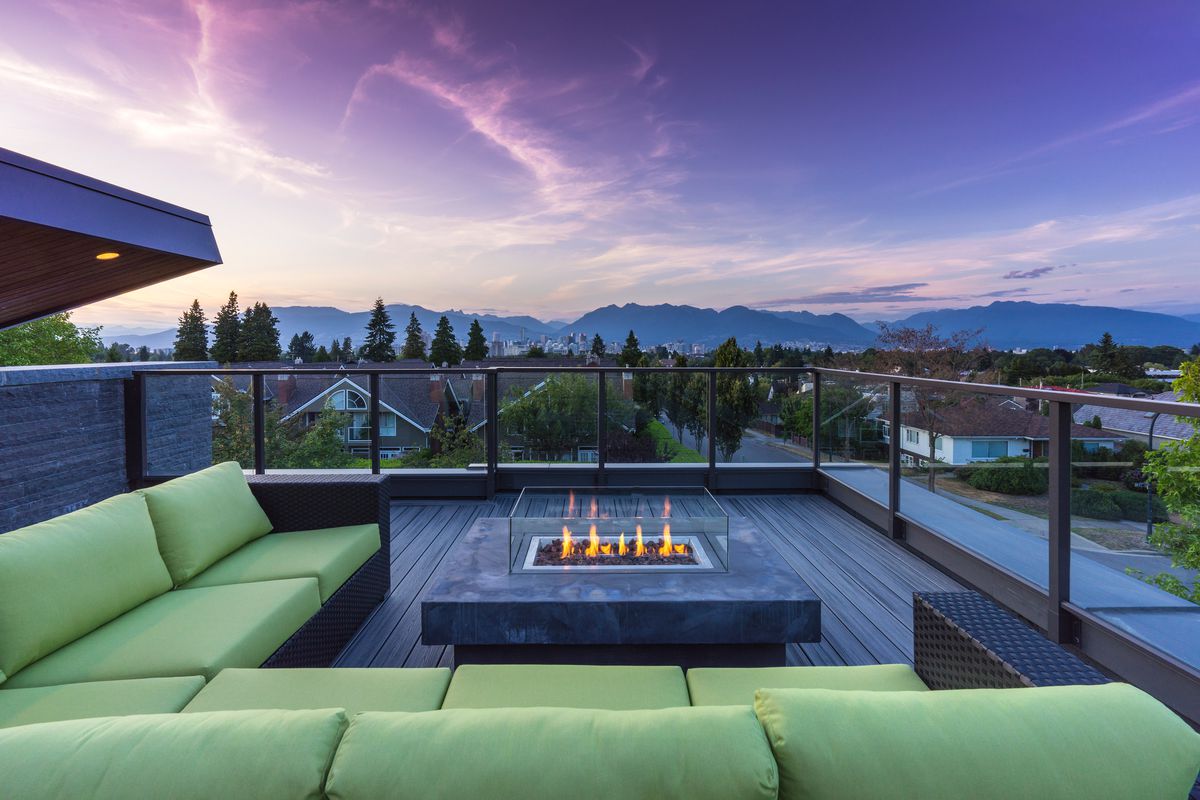 A rooftop deck with a firepit looking out to the mountains at sunset.