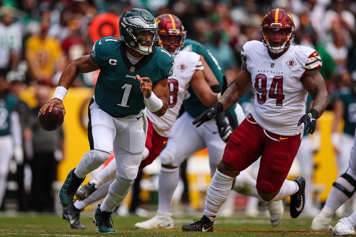 Jalen Hurts #1 of the Philadelphia Eagles scrambles from the pressure of Daron Payne #94 of the Washington Commanders during the first half at FedExField on September 25, 2022 in Landover, Maryland.