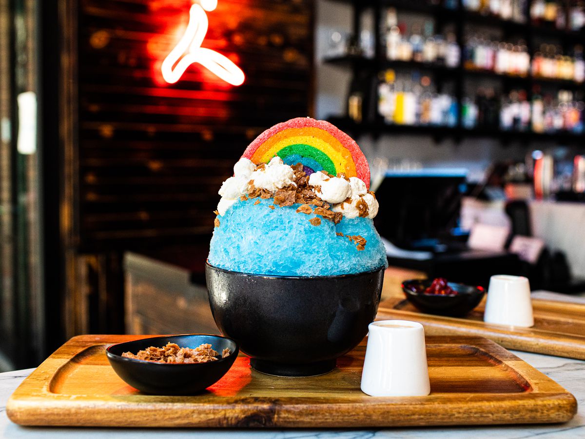 A blue shave ice dessert topped with a candy rainbow.