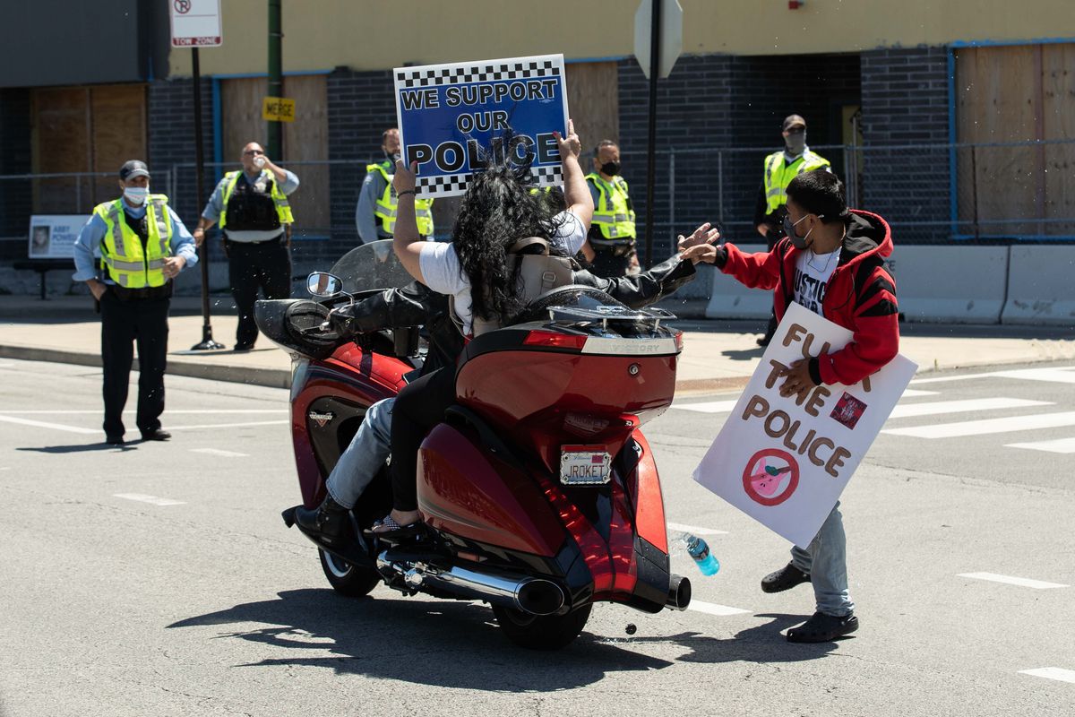 A protester splashes police supporters who were taunting and flipping off protesters with juice in front of the Jefferson Park district police station Saturday.