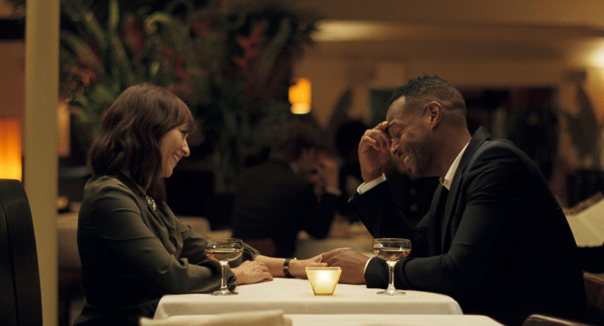 Rashida Jones and Marlon Wayans sit in a restaurant laughing together in On the Rocks