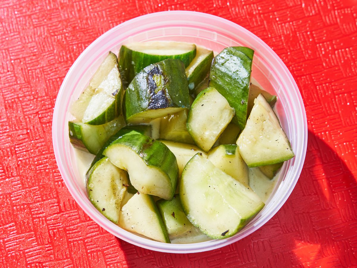 An overhead photograph of a plastic container filled with slices of cucumber.