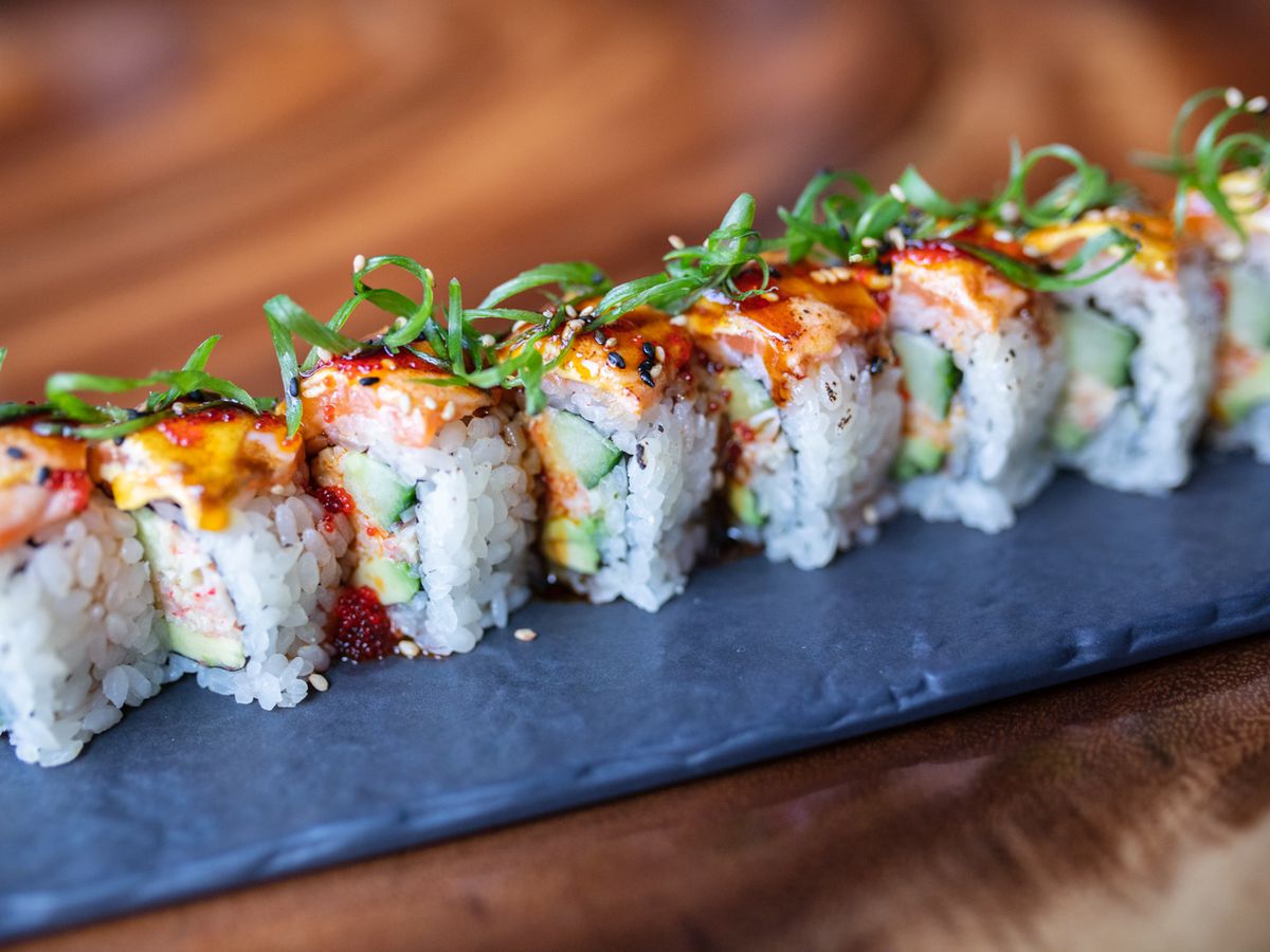 Eight pieces of sushi lined up on a gray slab.