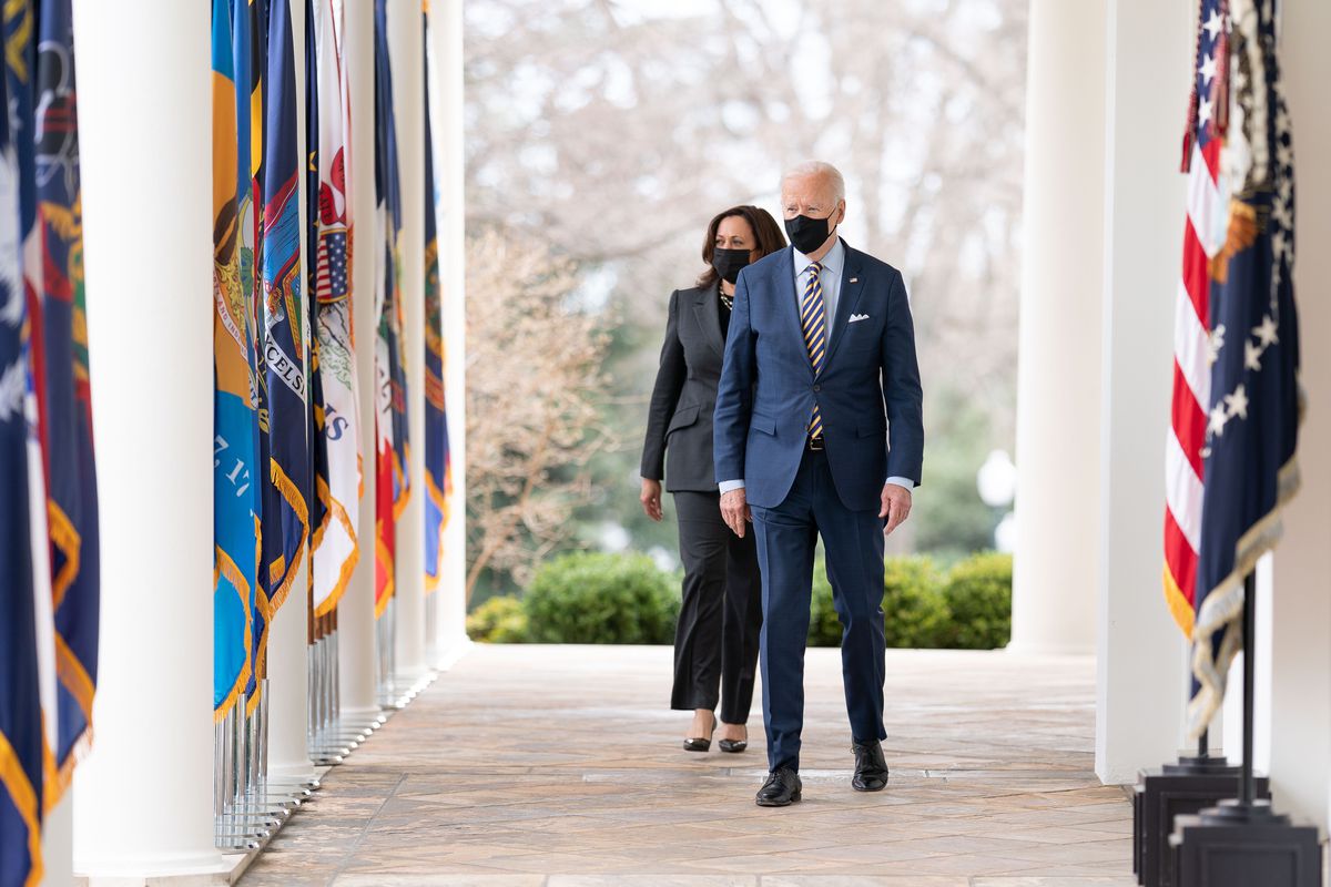 President Joe Biden and Vice President Kamala Harris walk from the Oval Office of the White House, both wearing masks.